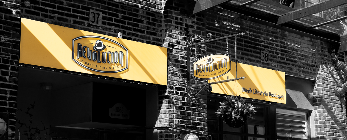Two yellow signs with 'Revolucion' branding on a brick building exterior.
